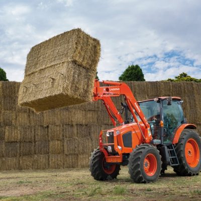 M Series Kubota Tractor with loader lifting bale